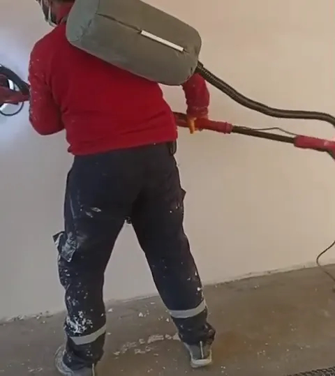 Usta, alçı zımpara makinasıyla duvar zımparalıyor